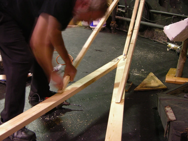 a man standing over wood to build a structure