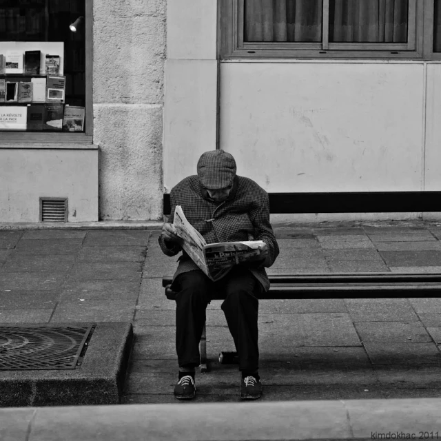 a man is sitting on a bench reading