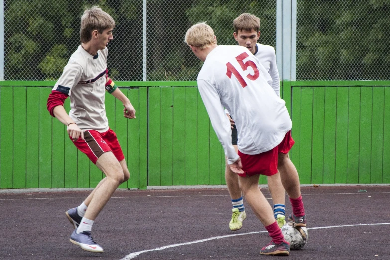 three boys play soccer on a school field