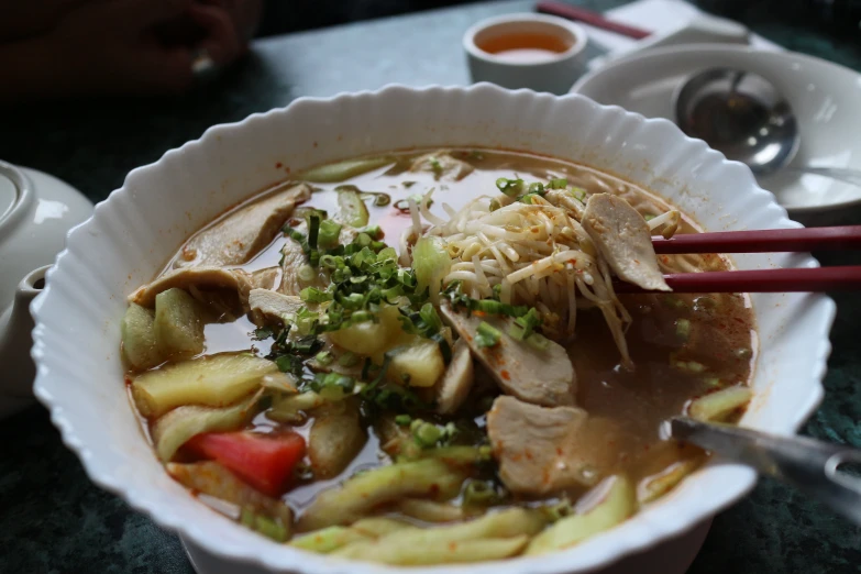 a bowl of soup with many toppings on a table