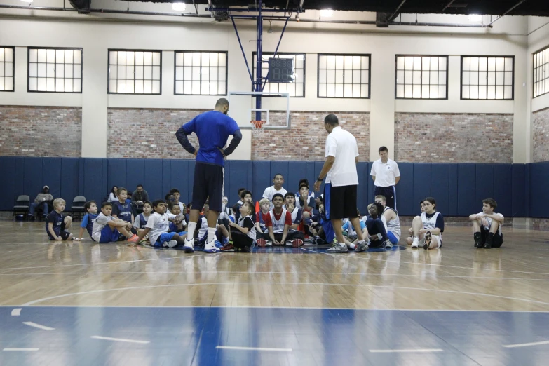 several boys in gymnasium watching basketball game with coach