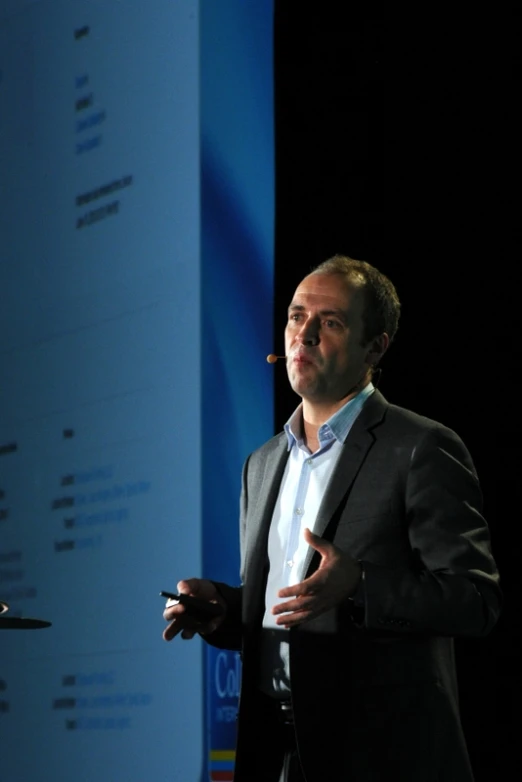 a man holding a cigarette on stage giving a presentation