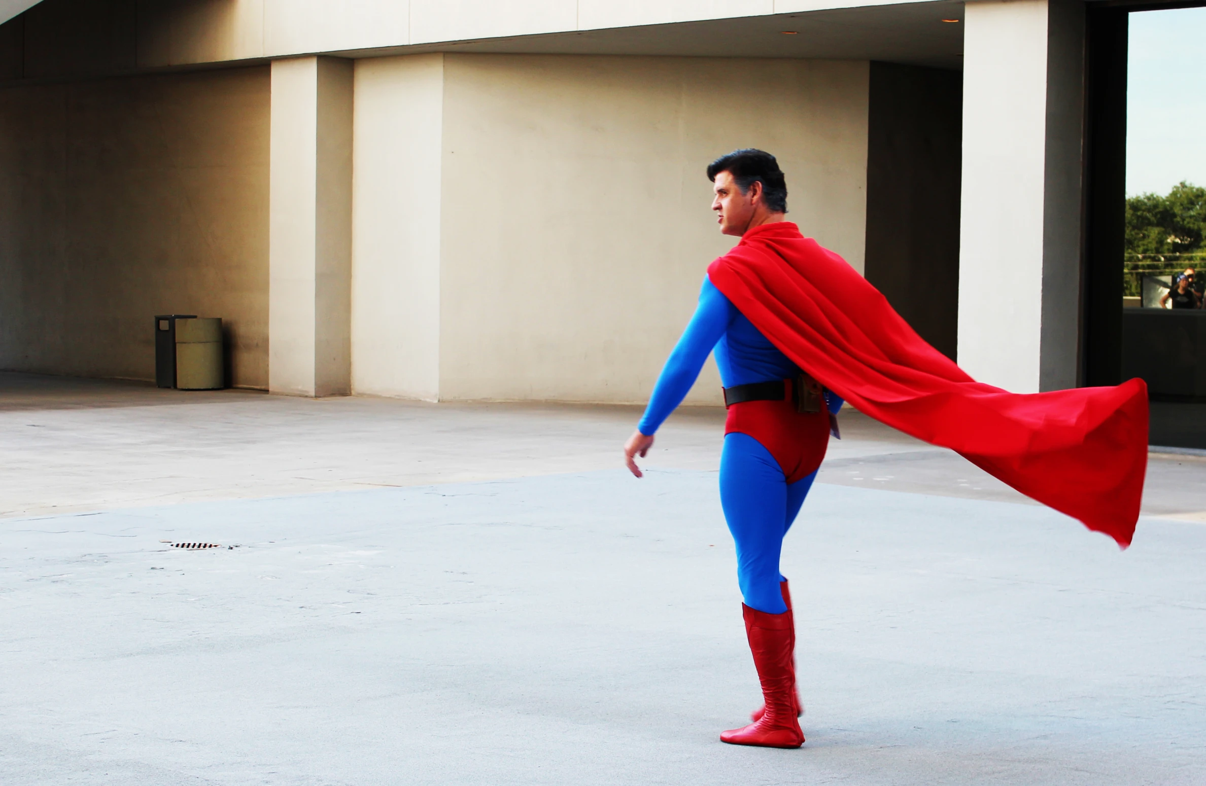 a man dressed in red and blue suit, has a cape over his head