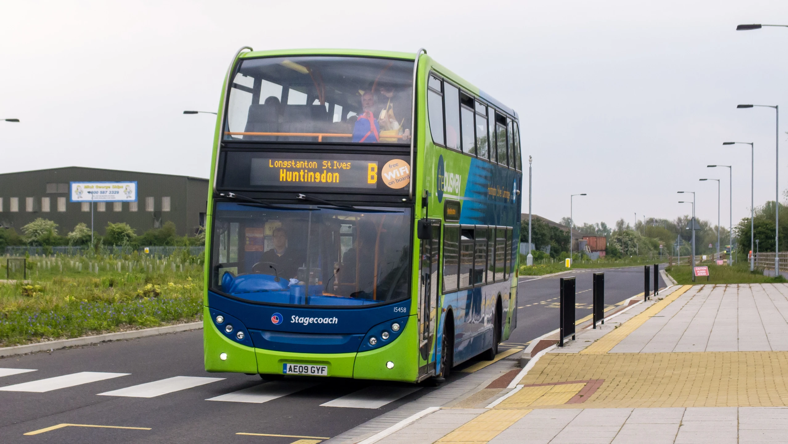 green double decker bus in roadway at urban area