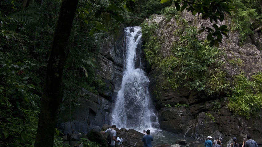 people are standing at the bottom of a small waterfall