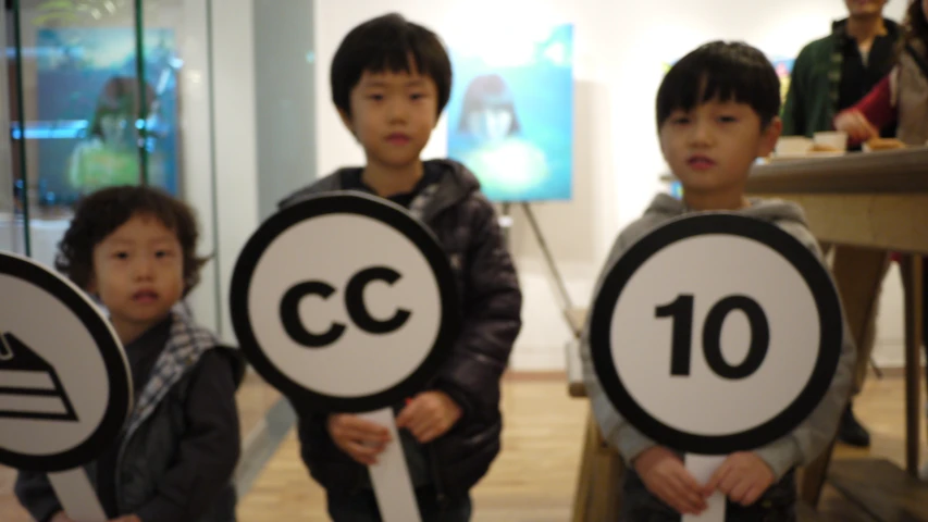 three children holding up various signs at an event