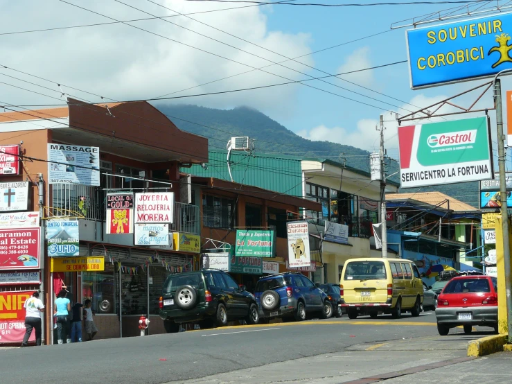 a street in a small town with many cars parked along the side