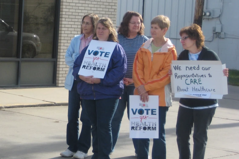 a group of people standing on the street holding signs