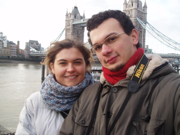 a young man and woman pose together with the cityscape in the background