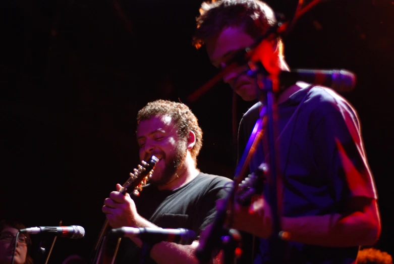 two men are singing in front of some microphones