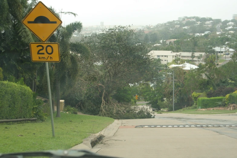 an upside down sign near the road in front of trees