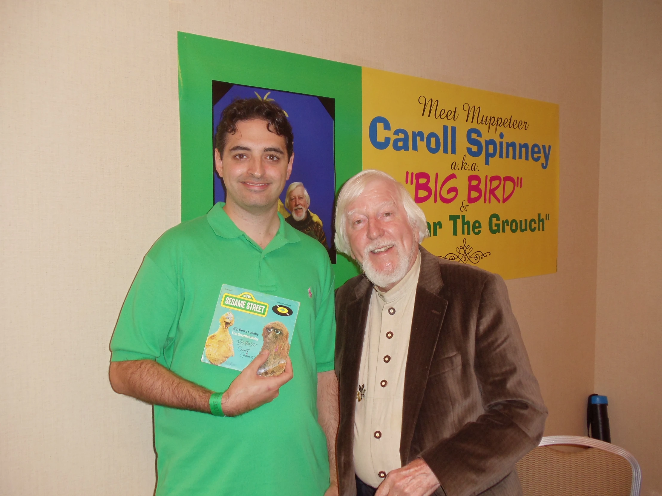 a man smiles and next to a man with an award