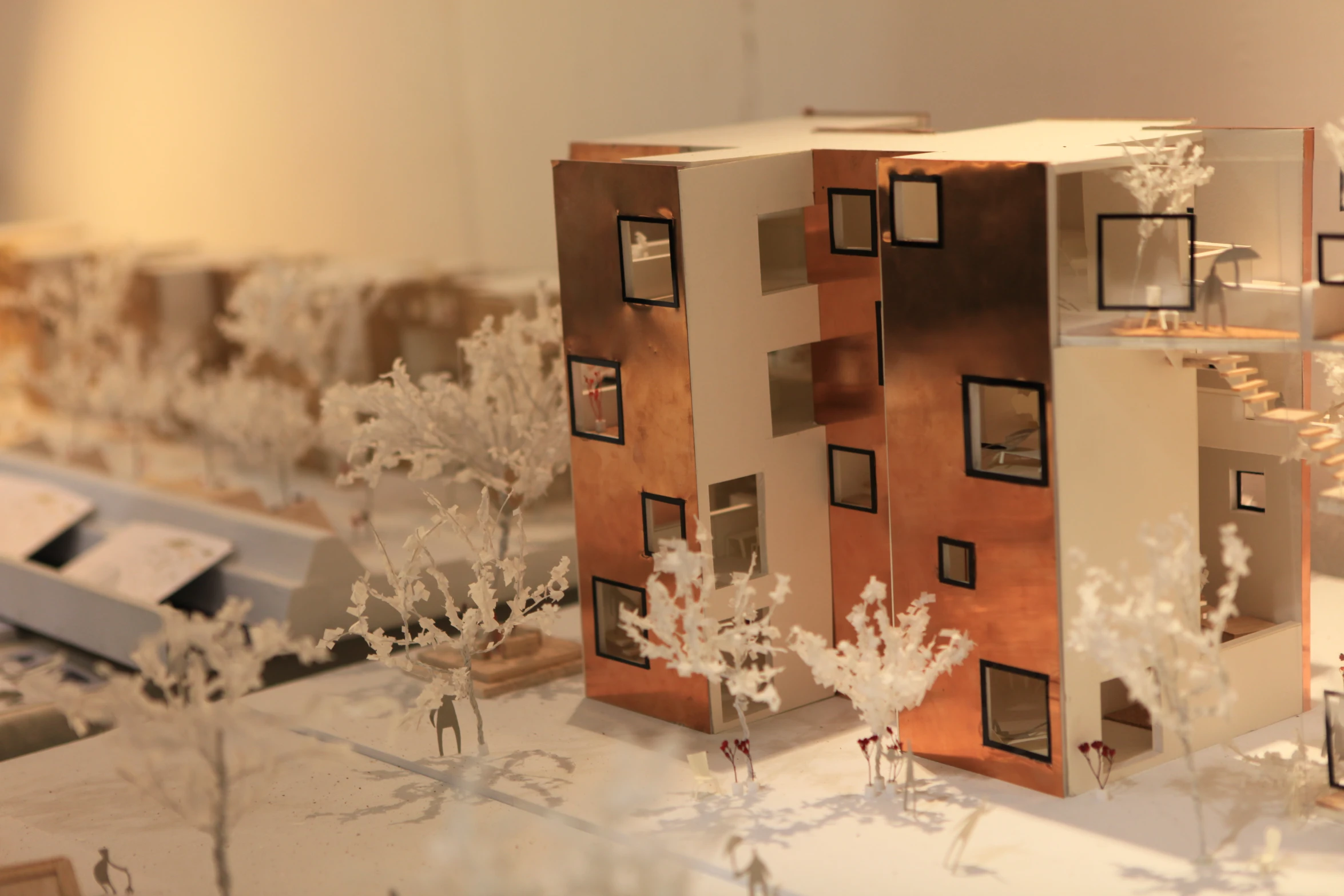 toy model of apartment building in front of trees with white flowers