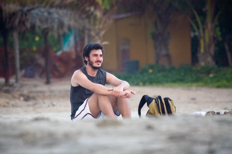 a young man sitting on a beach next to a banana