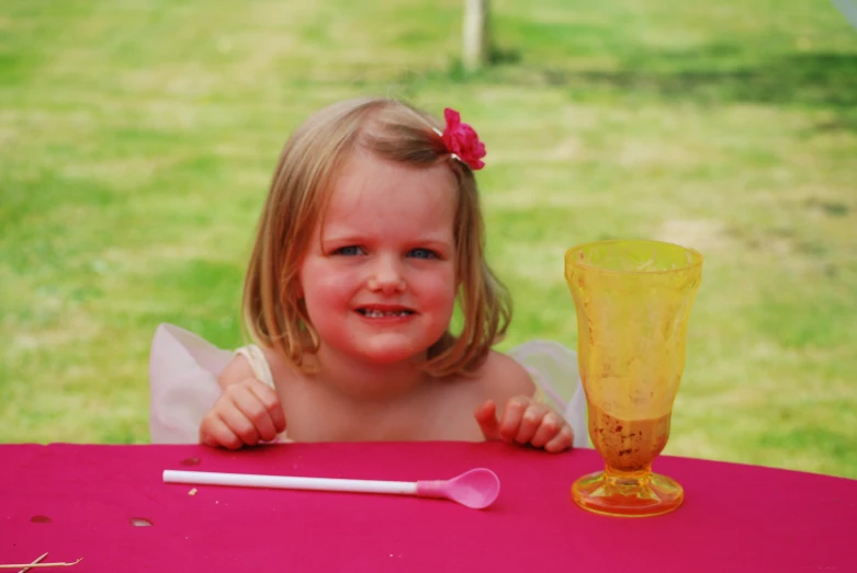 a little girl that is smiling at a table