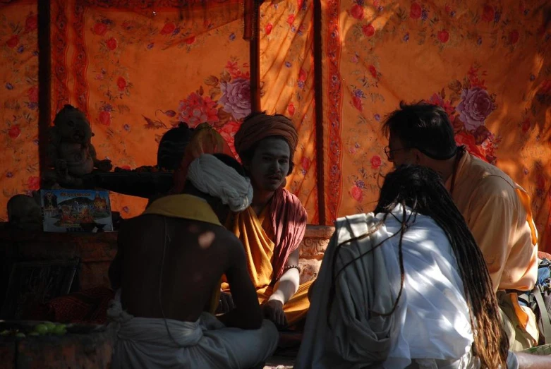 a man talking to another person in front of a tent