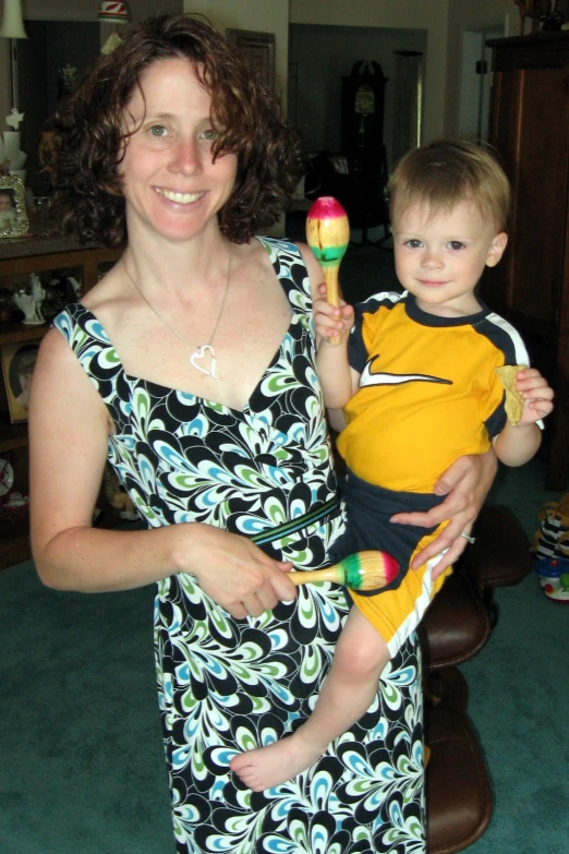 a woman holding a boy while they both wear different colored clothing