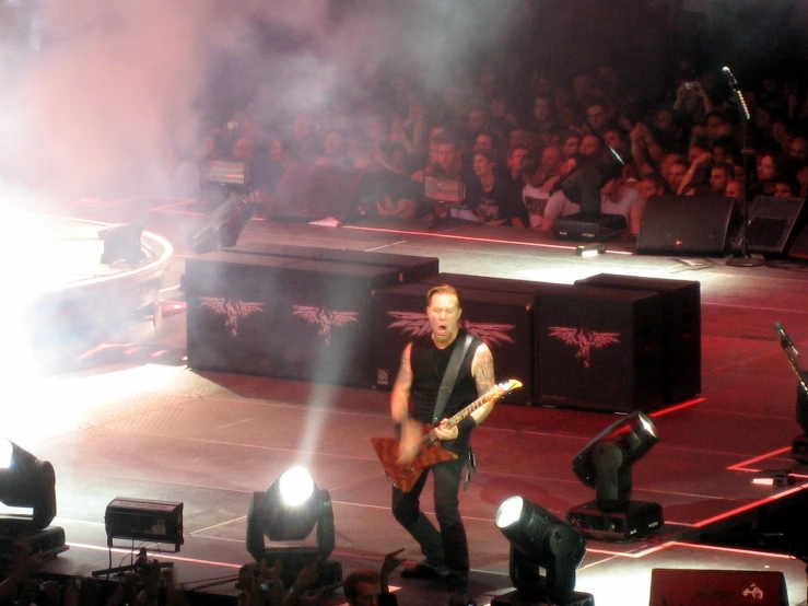 a man holding a guitar while standing on a stage