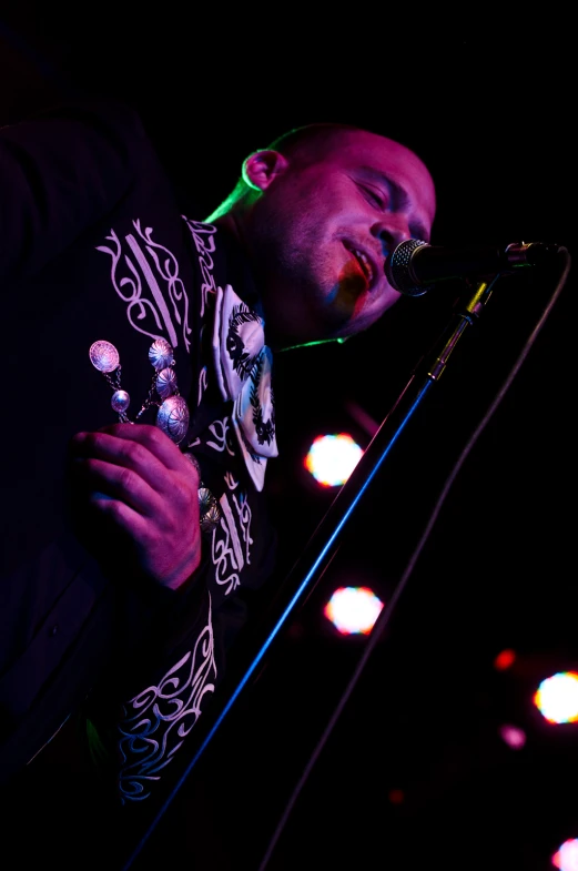 a man wearing a sweater holding a microphone and looking up