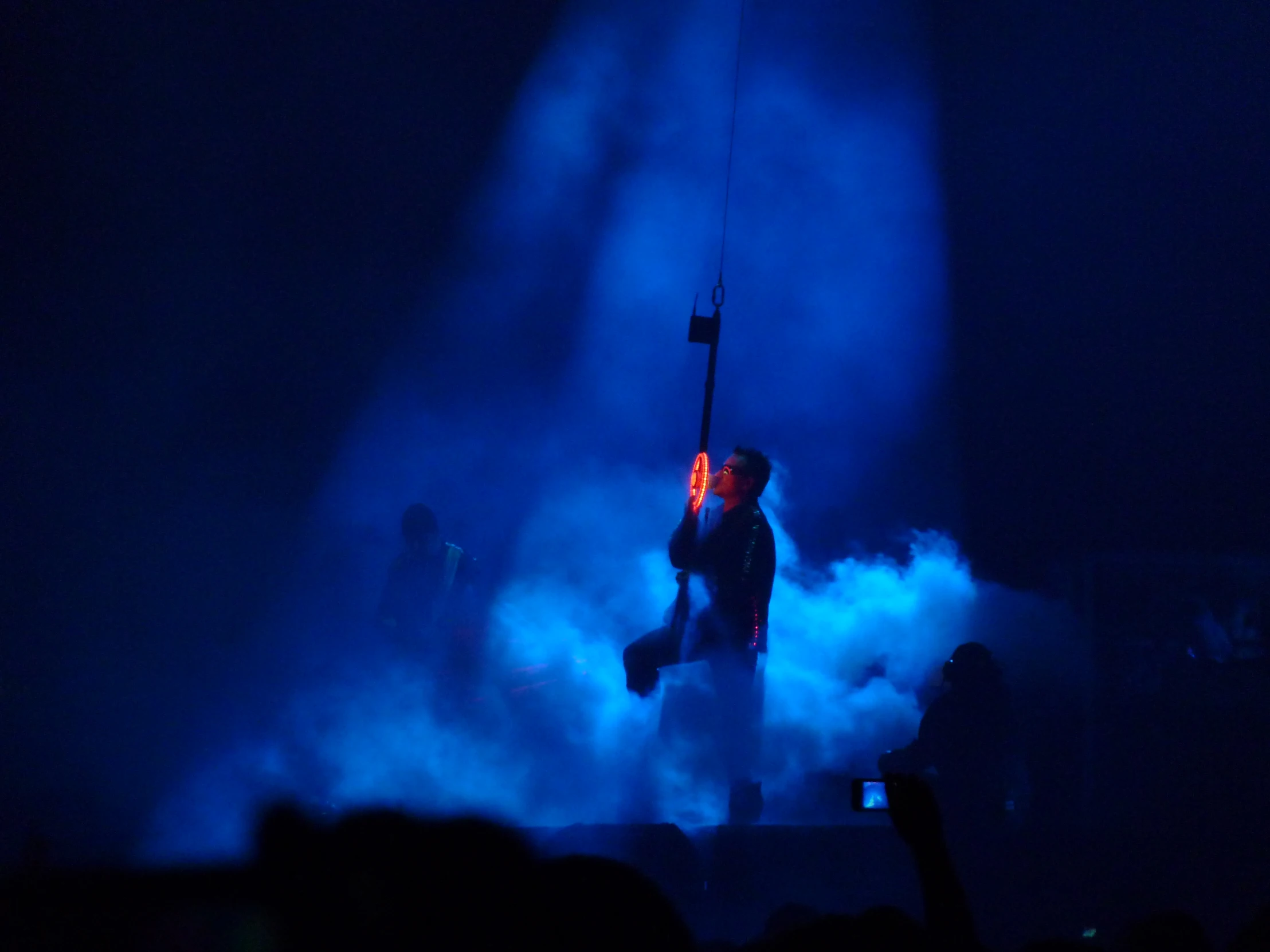 a man on stage holding a microphone in front of smoke