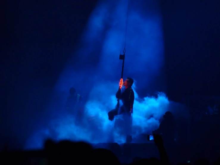 a man on stage holding a microphone in front of smoke