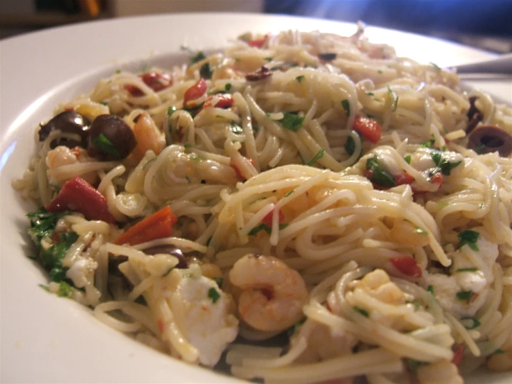 a white plate that has pasta and shrimp on it