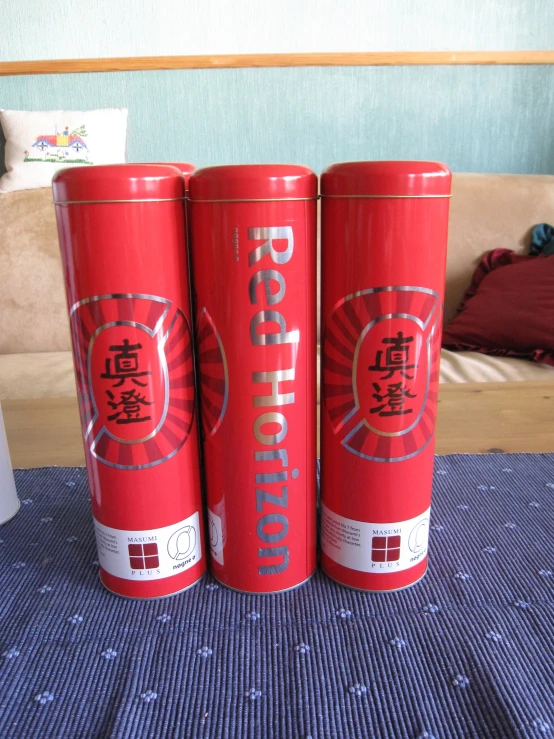 three cans of oriental tea sitting on a bed