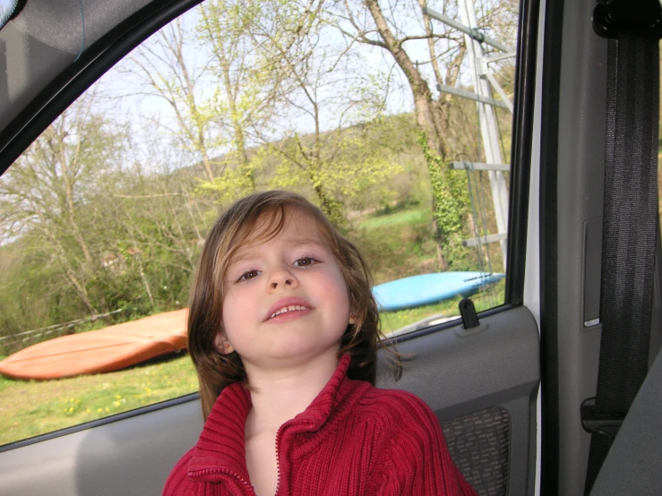 a young child is smiling from a car window