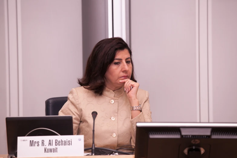 a woman in beige suit sitting at a table