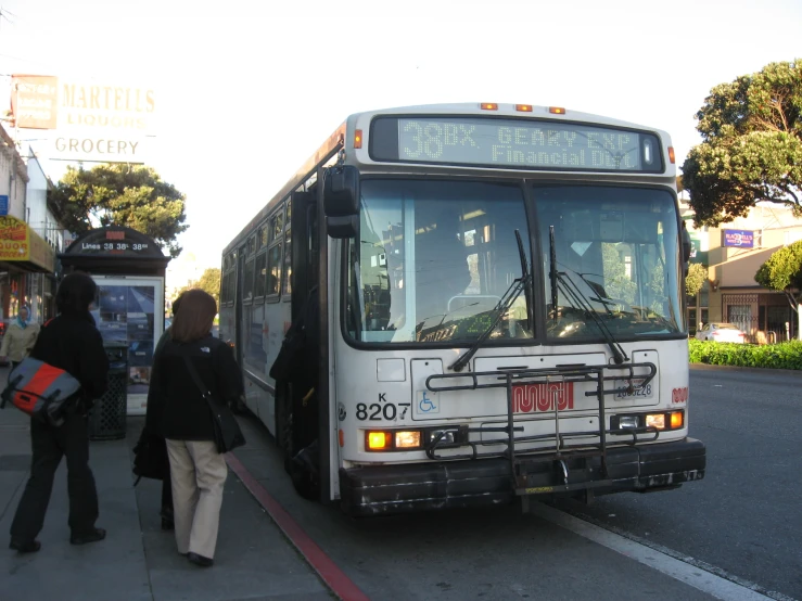 people wait to get on the bus at a bus stop