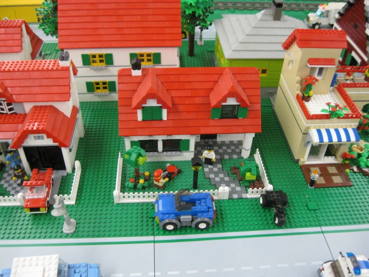 a lego model of houses with a truck and a lawn