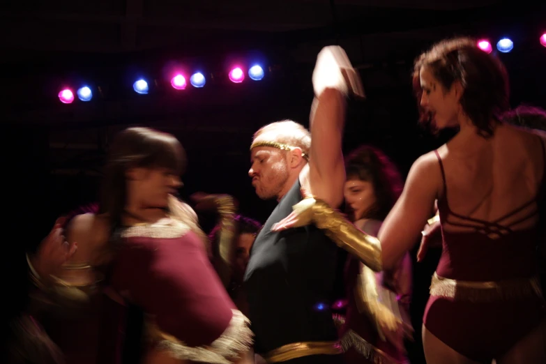 a man in a cosplay is holding an object while three women look on