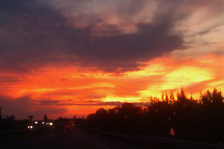 a sunset is shown over a street and trees