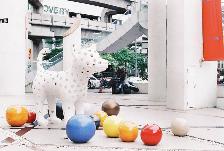 a ceramic giraffe standing between several balls on the ground