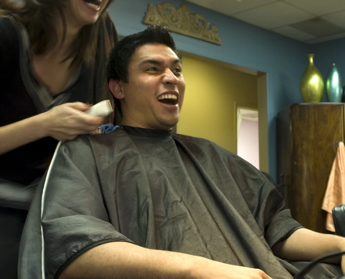 a man getting his hair brushed by a woman