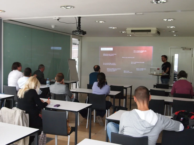 an overview image shows people listening to a presentation