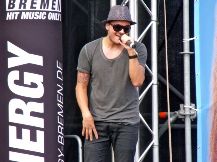 a man wearing sunglasses and hat while standing on stage