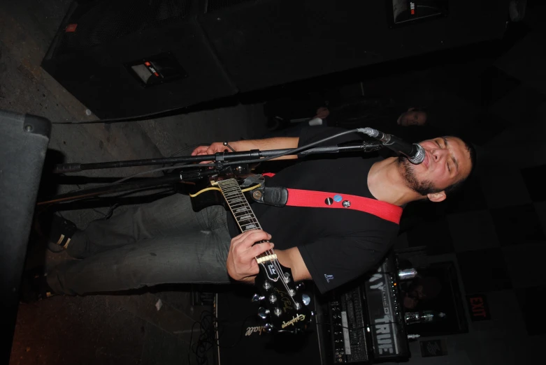 a man with a guitar sings into a microphone