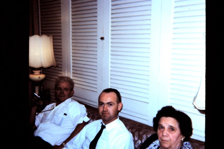 three adults sitting on a couch wearing dress clothes
