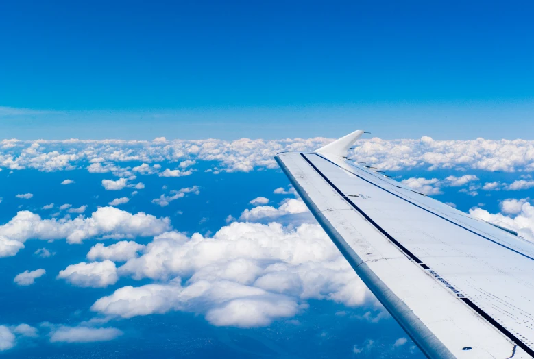 a window on the wing of an airplane above a cloud filled sky