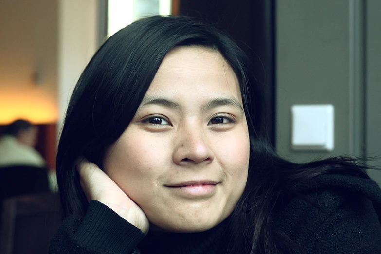 a woman sitting next to a wall wearing black