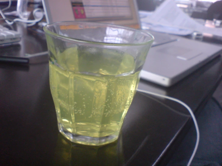 a glass of tea on a desk with a laptop in the background