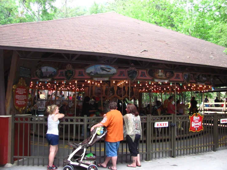 a carousel with people standing near by looking at it