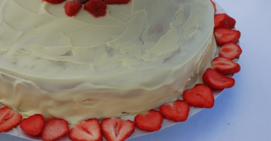 a large cake with several cut strawberries on the cake