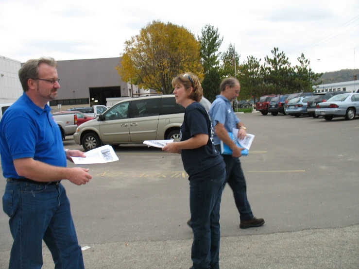 three people are walking in a parking lot while one holds a piece of paper