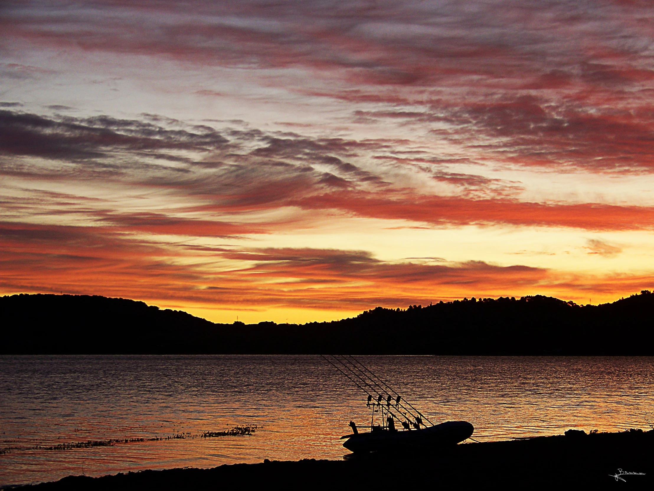 boats are docked at the shore as the sun is setting