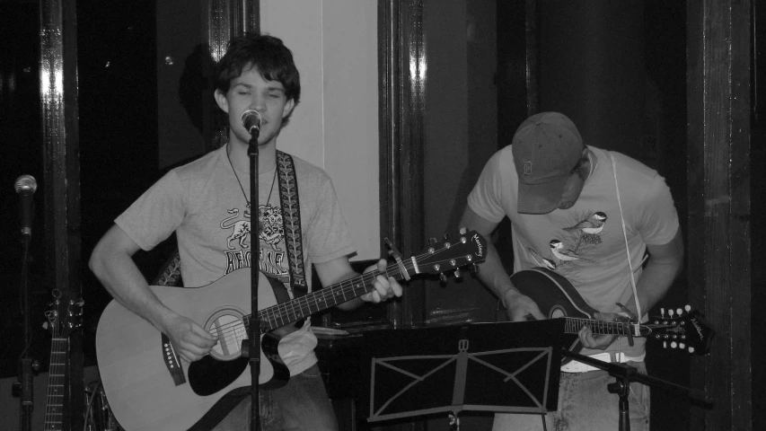 two men are playing guitars in the middle of a room