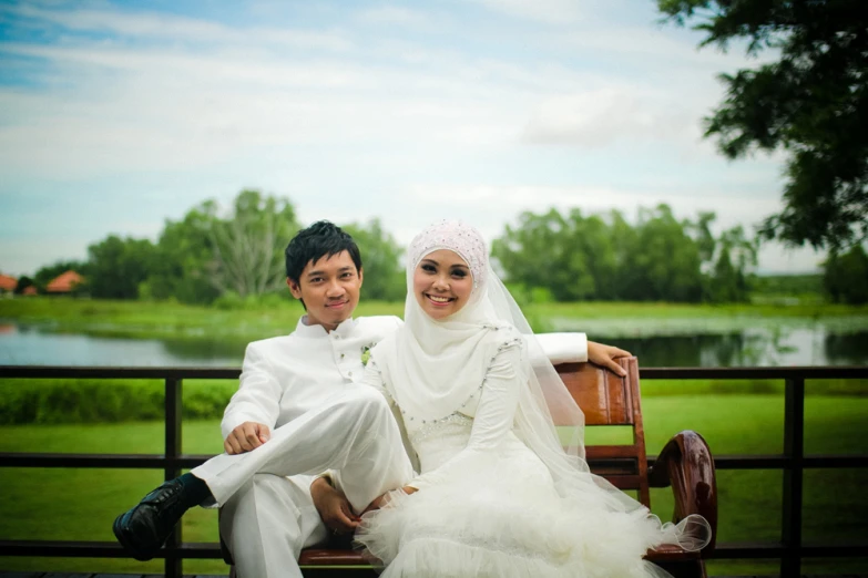 two people sitting on a bench smiling at the camera