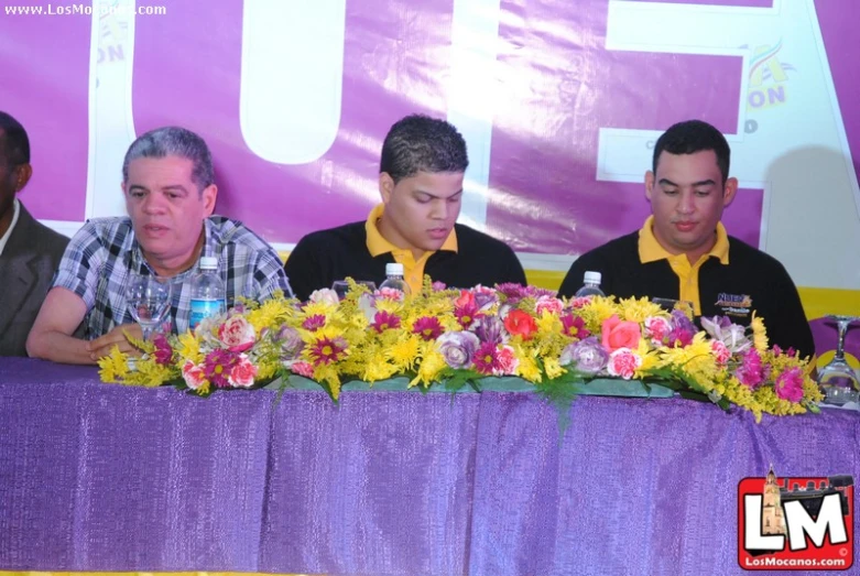 three men are standing at the side of a large table