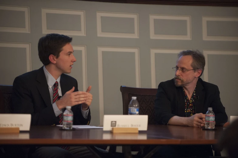 two men sit in front of a meeting table